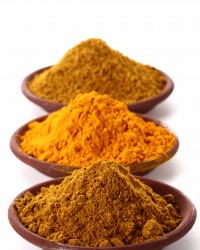 piles of bright Curry Powder and tumeric in teracotta dish